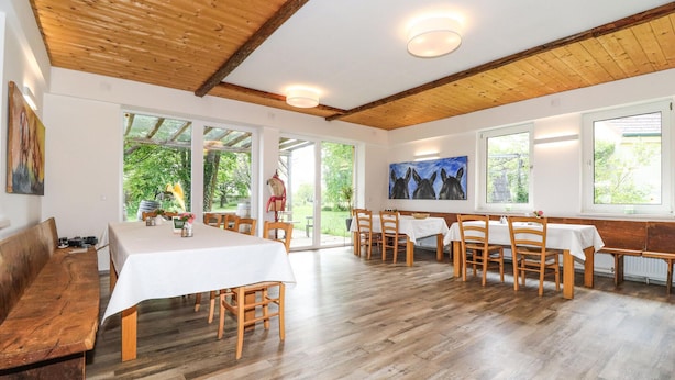 A dining area with wooden tables and chairs, large windows, and a wooden ceiling. - 2 bedroom nice apartment in Kroatisch Minihof (Kroatisch Minihof)