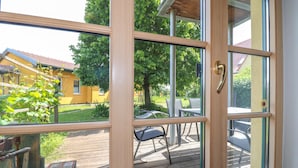 A wooden-framed window with a view of a deck, outdoor furniture, and a yellow building. - 2 bedroom nice apartment in Kroatisch Minihof (Kroatisch Minihof)