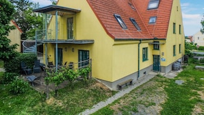 A yellow building with a red roof, a balcony, and a small garden area. - 2 bedroom nice apartment in Kroatisch Minihof (Kroatisch Minihof)