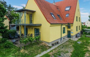 Un edificio giallo con tetto rosso, un balcone e un piccolo giardino.