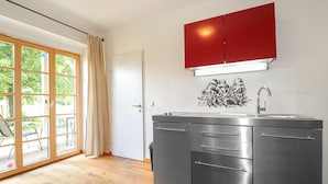 A modern kitchen with a stainless steel countertop, a red cabinet above, and a window with a view of greenery. - 2 bedroom nice apartment in Kroatisch Minihof (Kroatisch Minihof)