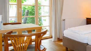 A room with a bed, a table, and chairs, a window with a view of greenery, and a radiator. - 2 bedroom nice apartment in Kroatisch Minihof (Kroatisch Minihof)