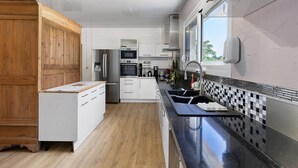 Una cocina moderna con armarios blancos, encimera negra y salpicadero a cuadros.