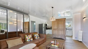 Un amplio salón con un sofá de cuero marrón, una mesa de centro de vidrio y un mueble de madera.