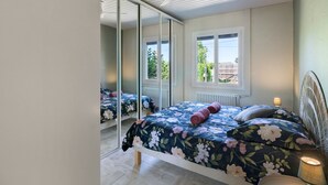 Un dormitorio con cama, espejo, ventana y ventilador de techo.