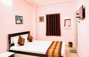 A bedroom with a bed, a TV, a picture on the wall, and a curtain. - Hotel Jagannath Inn Puri (Puri)