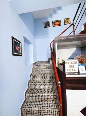 A staircase with patterned tiles, a wooden handrail, and a checkout sign indicating a time of 8:00 A.M. - Hotel Jagannath Inn Puri (Puri)