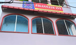 A building with a sign for Hotel Jagannath Inn, featuring arched windows with mesh screens. - Hotel Jagannath Inn Puri (Puri)