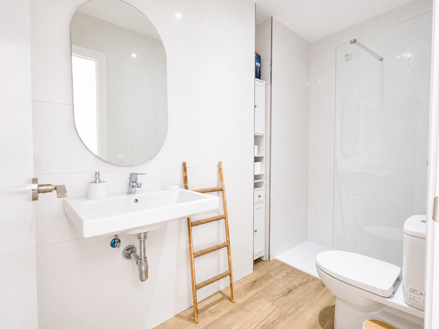 A modern bathroom with a white sink, mirror, toilet, and shower.