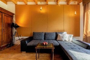 A cozy living room with a sectional sofa, a coffee table, and a lamp. - Private Apartment—Near Strasbourg—Baden-Baden (Rheinau)