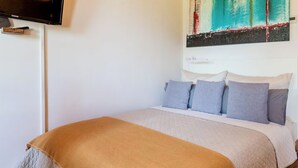 Una camera da letto con un letto, una televisione e un quadro appeso al muro.