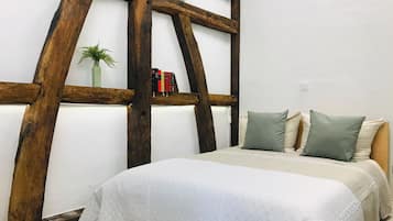 Une chambre à coucher avec un lit, des oreillers, une bibliothèque et une plante.