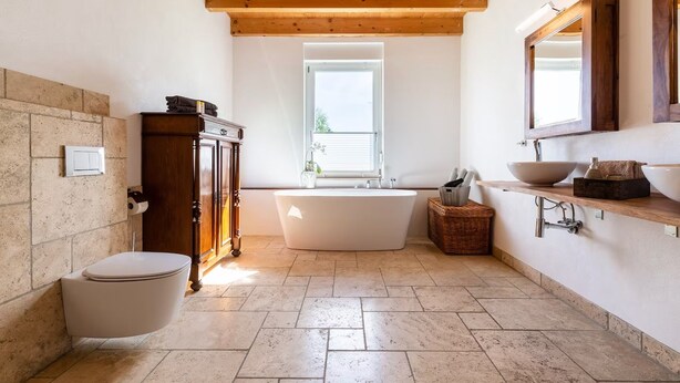 Un bagno con una vasca da bagno indipendente, un armadietto in legno e un grande specchio sopra il lavandino.