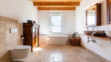 Une salle de bain avec une baignoire sur pieds, un meuble en bois et un grand miroir au-dessus du lavabo.