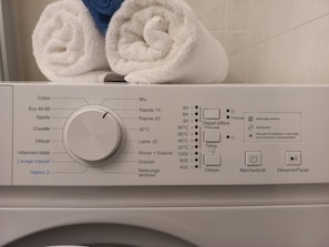 Une machine à laver à chargement frontal, dotée de différents programmes et d’un bouton de commande.