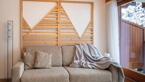 Un divano dai toni neutri con una coperta, una parete con listelli di legno e una finestra vista alberi.