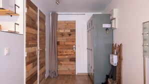 Un corridoio con pavimento in legno, parete grigia e porta in legno.