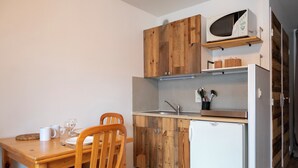Una cucina compatta con mobili in legno, un forno a microonde, un lavello e un'area pranzo con tavolo e sedie.