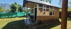 A small, single-story building with a covered porch, a door, and a window. - Vatika Resorts Cottages (Shoghi)