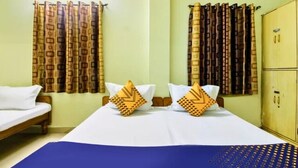 Ein Zimmer mit einem Bett, zwei Kissen mit geometrischem Muster, Vorhängen mit geometrischem Muster und einem Kleiderschrank.