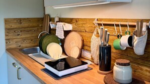 Una cocina con encimera de madera, horno integrado, colgador de ollas y un lavamanos pequeño.