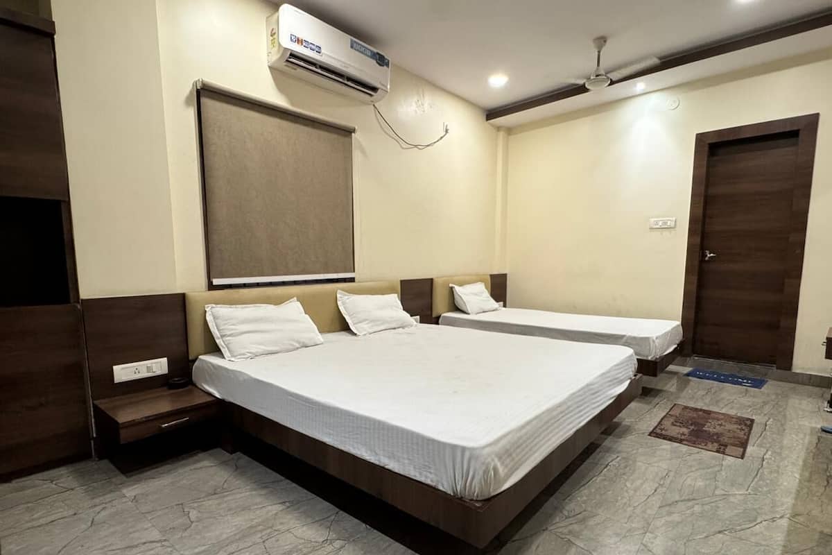 Habitación de hotel con dos camas, ventilador de techo, equipo de aire acondicionado y suelo de mármol.