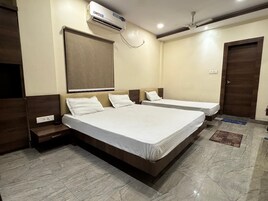 Habitación de hotel con dos camas, ventilador de techo, equipo de aire acondicionado y suelo de mármol.