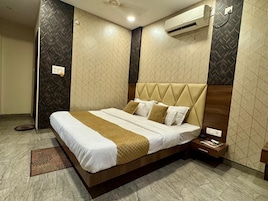 Una habitación de hotel con cama, mesita de noche, equipo de aire acondicionado y paredes con diseño.