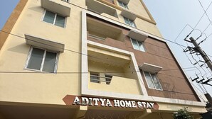 Un edificio de varios pisos con un letrero que dice 'ADITYA HOME STAY'.