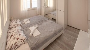 A bedroom with a bed, a wardrobe, a mirror, and a window. - Nice apartment in Jesenice with lake view (Jesenice)