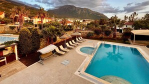 Ein Poolbereich mit Liegestühlen, einem kleinen Pool und einer Bergkulisse.