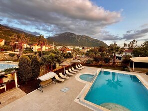 Ein Poolbereich mit Liegestühlen, einem kleinen Pool und einer Bergkulisse.