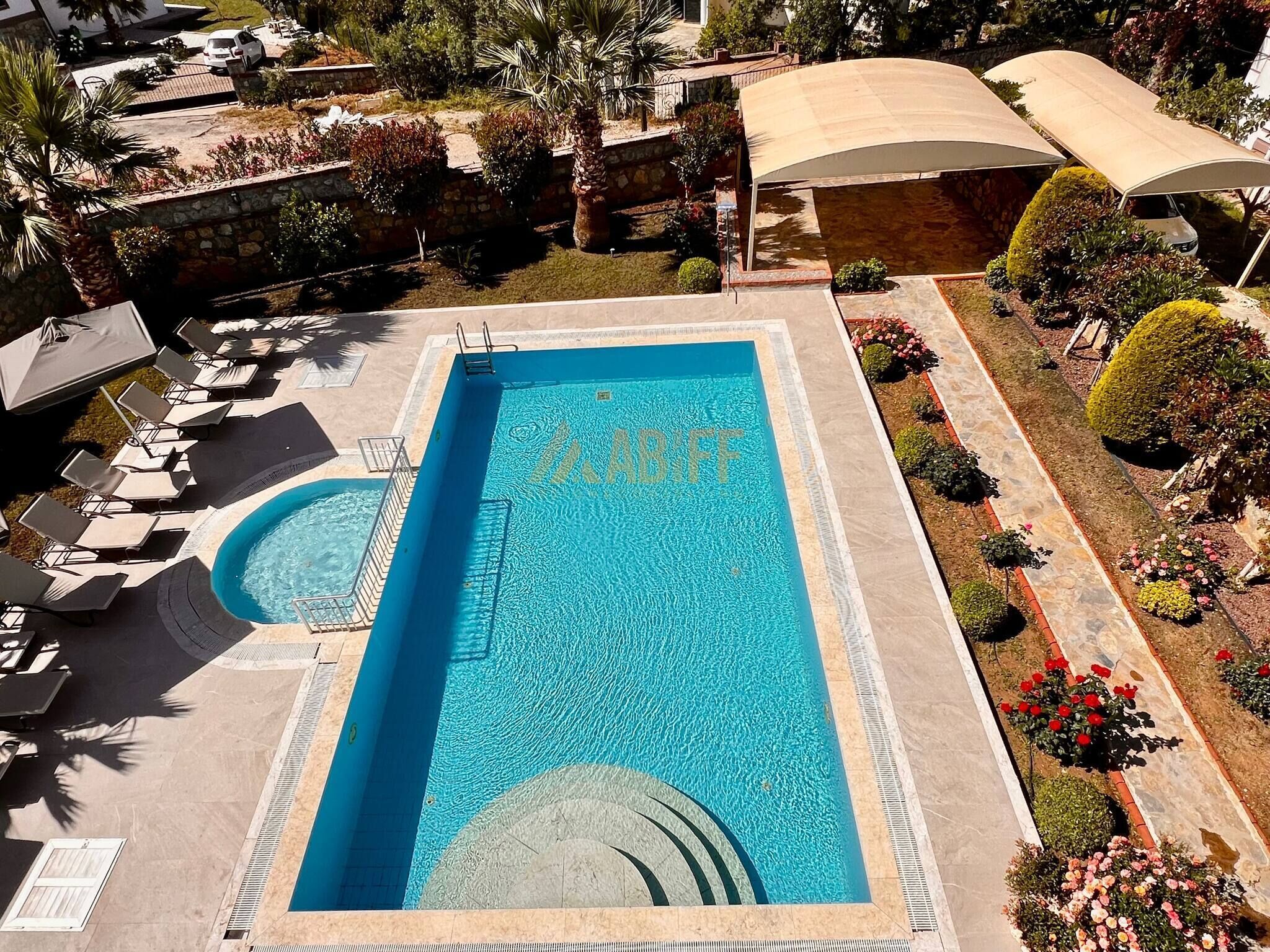 A rectangular swimming pool with a clear blue water surface, surrounded by a stone deck.