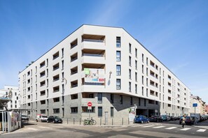 A multi-story building with balconies, a pedestrian crossing, and parked cars. - Zenao Appart'hôtels Lyon 7 (Lyon)