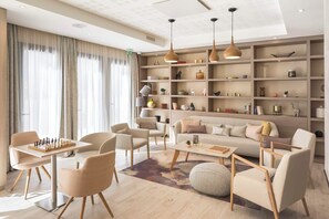 A modern living room with a sofa, chairs, a coffee table, a chessboard, and a bookshelf. - Zenao Appart'hôtels Lyon 7 (Lyon)