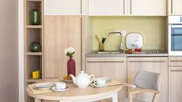 Una cocina moderna con una mesa de comedor, sillas, un lavamanos y un reloj.