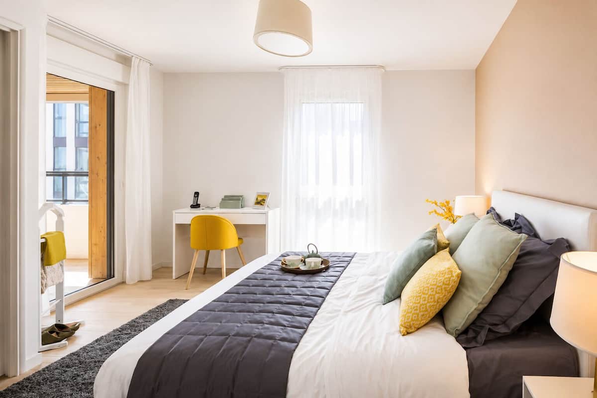 Un dormitorio con cama, escritorio, silla y ventana.