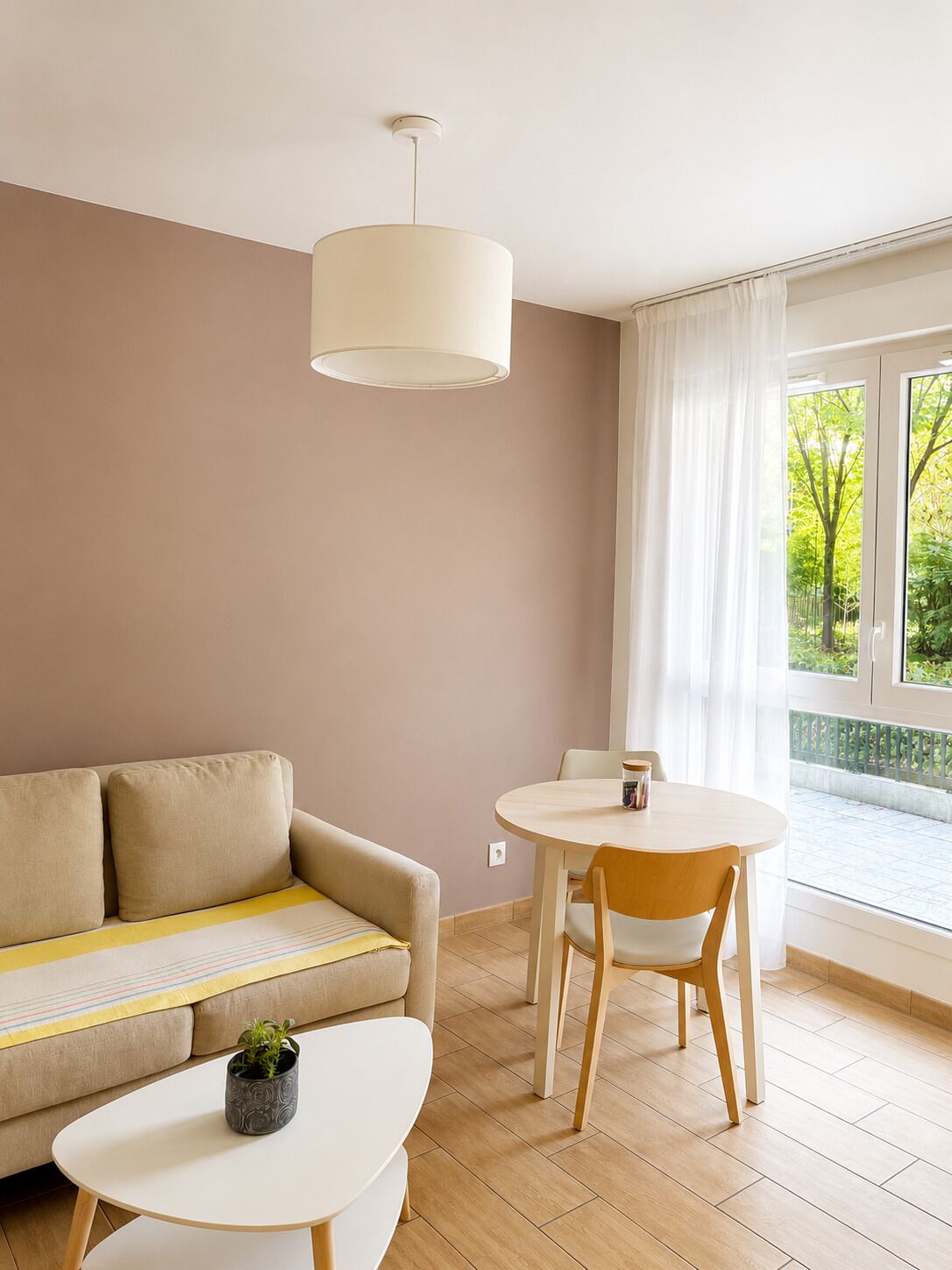 A modern living room with a sofa, a round dining table, and a pendant light.