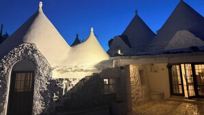A traditional building with conical roofs, a stone entrance, and a tiled patio area. - ALVICA  (Martina Franca)
