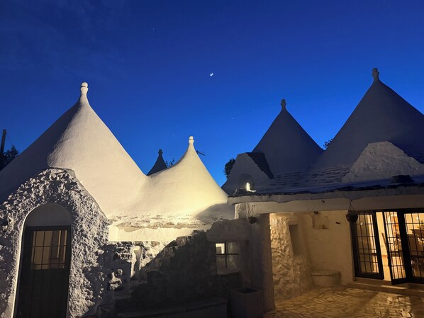 A traditional building with conical roofs, a stone entrance, and a tiled patio area.