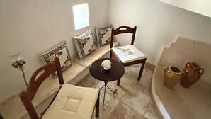 A small, well-lit room with a round table, two chairs, a small potted plant, and decorative pillows. - ALVICA  (Martina Franca)