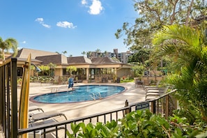A pool area with lounge chairs, a pool with a diving board, and a sign indicating pool rules. - Ocean-view 1BR condo with pool, lanai, and full kitchen- Valley Isle 1001 (Lahaina)