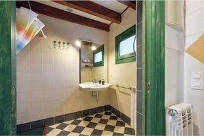 Un baño con suelo a cuadros, un lavabo, un espejo y un radiador.