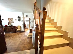 A staircase with wooden balusters and a handrail, leading to a landing with a radiator and a chair. - SUN HOUSE MONTORSO-OASIS OF RELAXATION A STONE'S THROW FROM THE SEA (LORETO)