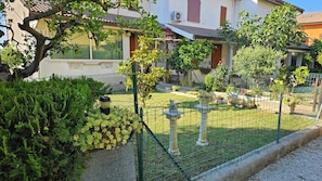 A residential area with a fenced garden, a stone fountain, and a building with a tiled roof. - SUN HOUSE MONTORSO-OASIS OF RELAXATION A STONE'S THROW FROM THE SEA (LORETO)