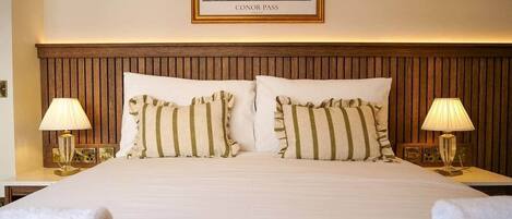 Une chambre d’hôtel avec un grand lit, deux lampes de chevet, un tableau encadré au mur et un lit soigneusement fait avec des serviettes.