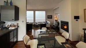 Una sala de estar moderna con chimenea, un comedor con mesa de vidrio y una cocina con armarios y encimera.