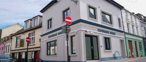 A building with a 'No Entry' sign, a shop named 'Experience Dinges,' and a car parked on the street.