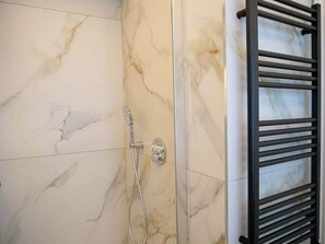 Ein Badezimmer mit Dusche, Handtuchhalter und Marmorwänden.