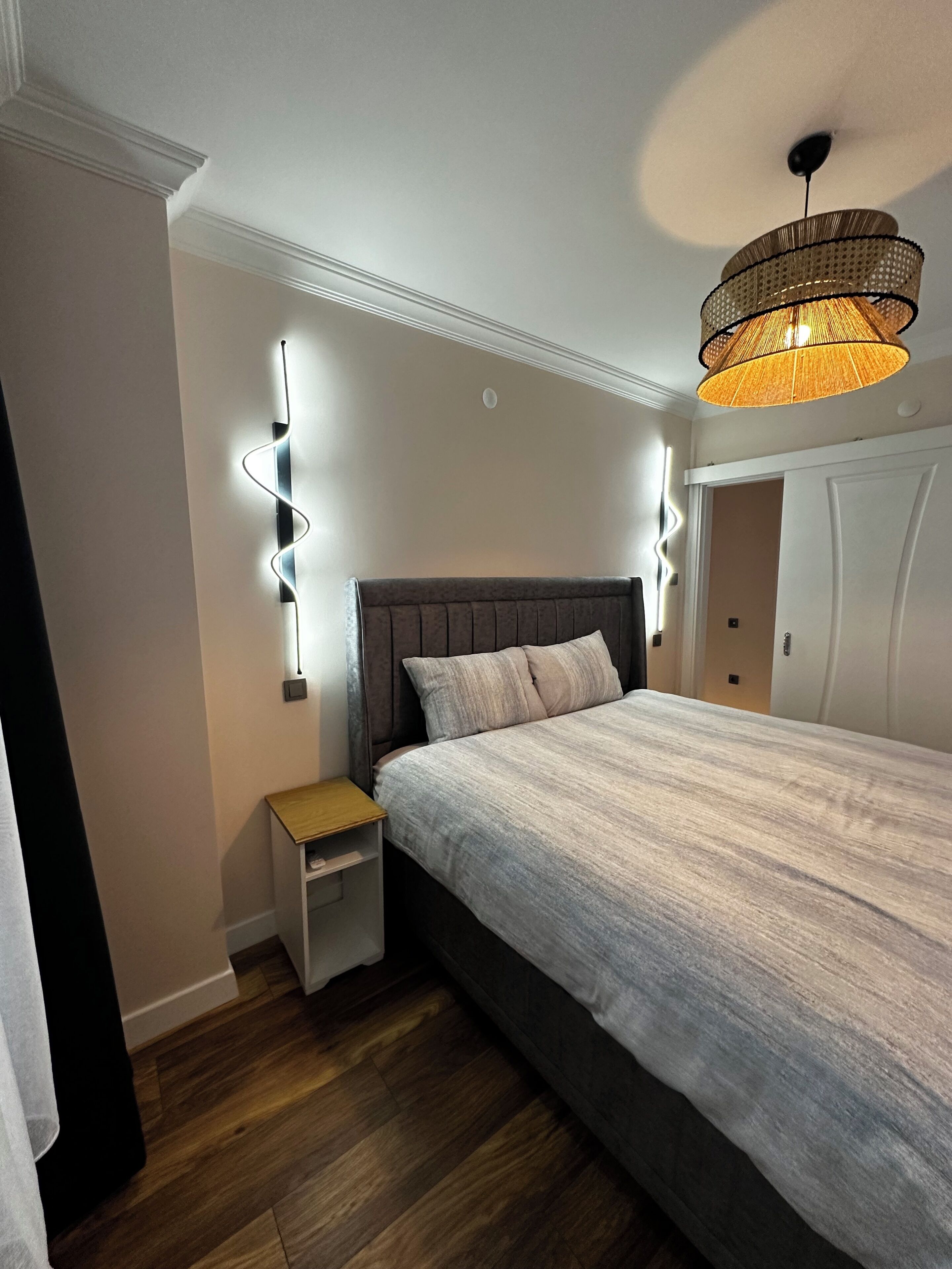 A bedroom with a bed, bedside tables, a hanging light fixture, and a ceiling fan.